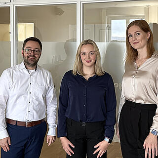 burgenta-Partner Philip und Steuerberaterin Gyde stehen gemeinsam mit Schülerin Emelie in den Räumlichkeiten von burgenta.