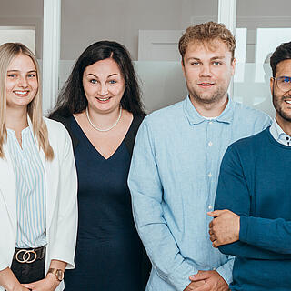 Gruppenfoto der vier burgenta-Mitarbeitenden Sina, Melanie, Jannes und Ahmad.