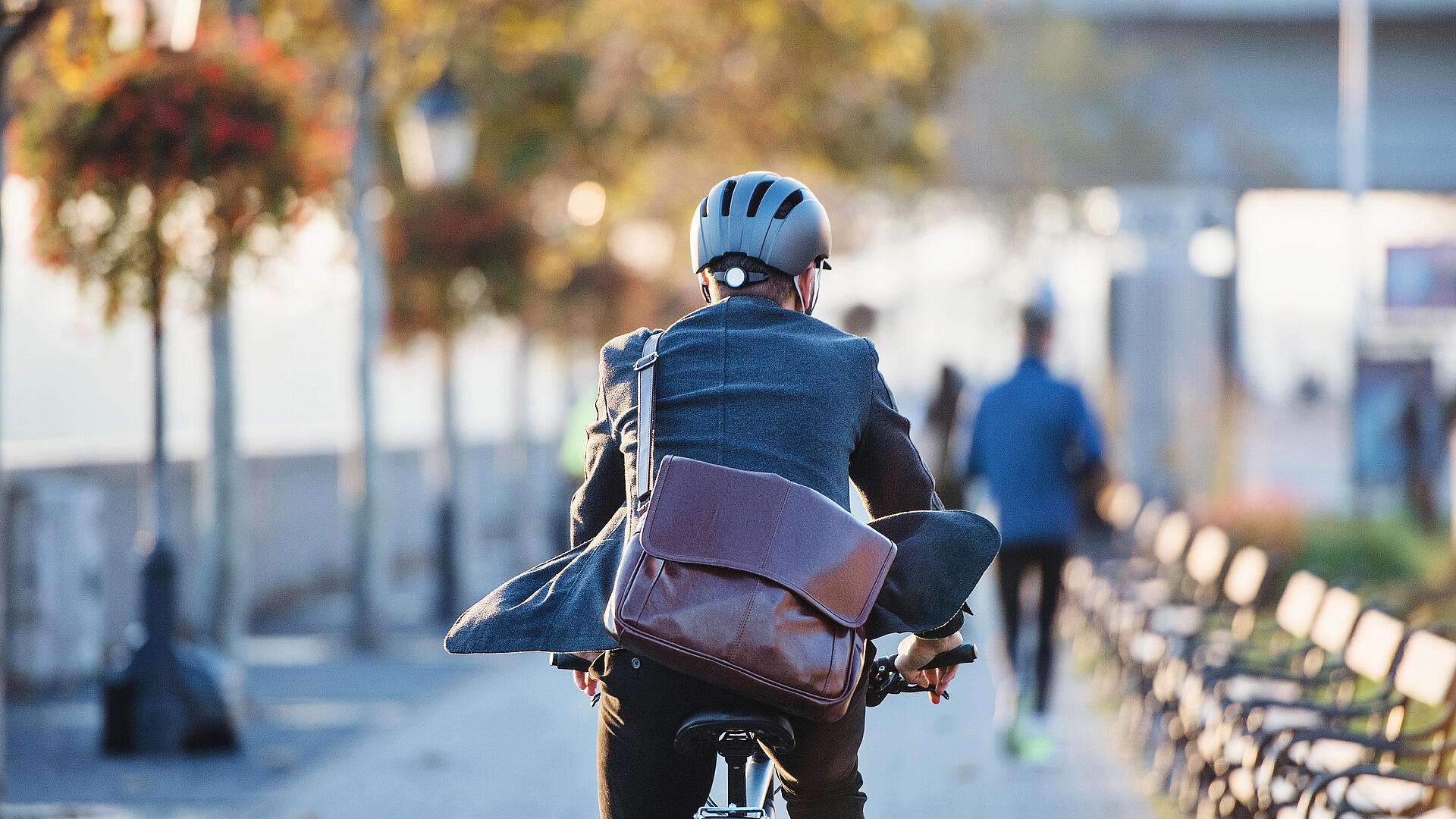 Ein Mann mit Aktentasche fährt auf einem Fahrrad. 