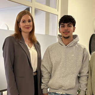 burgenta Steuerberaterin und die beiden Praktikanten stehen fröhlich lächelnd im Büro